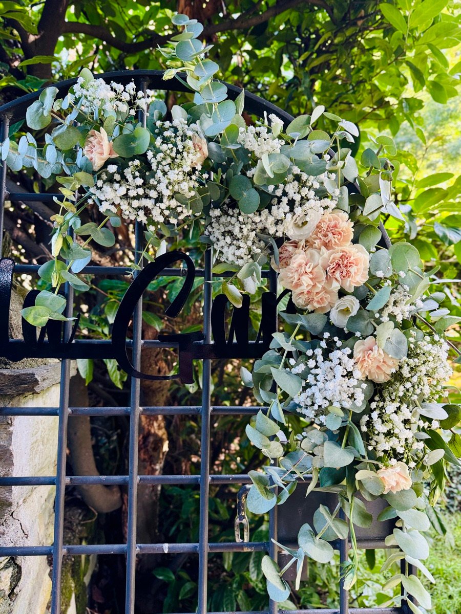 Allestimento floreale per matrimonio: cancello decorato con eucalipto e garofani pesca